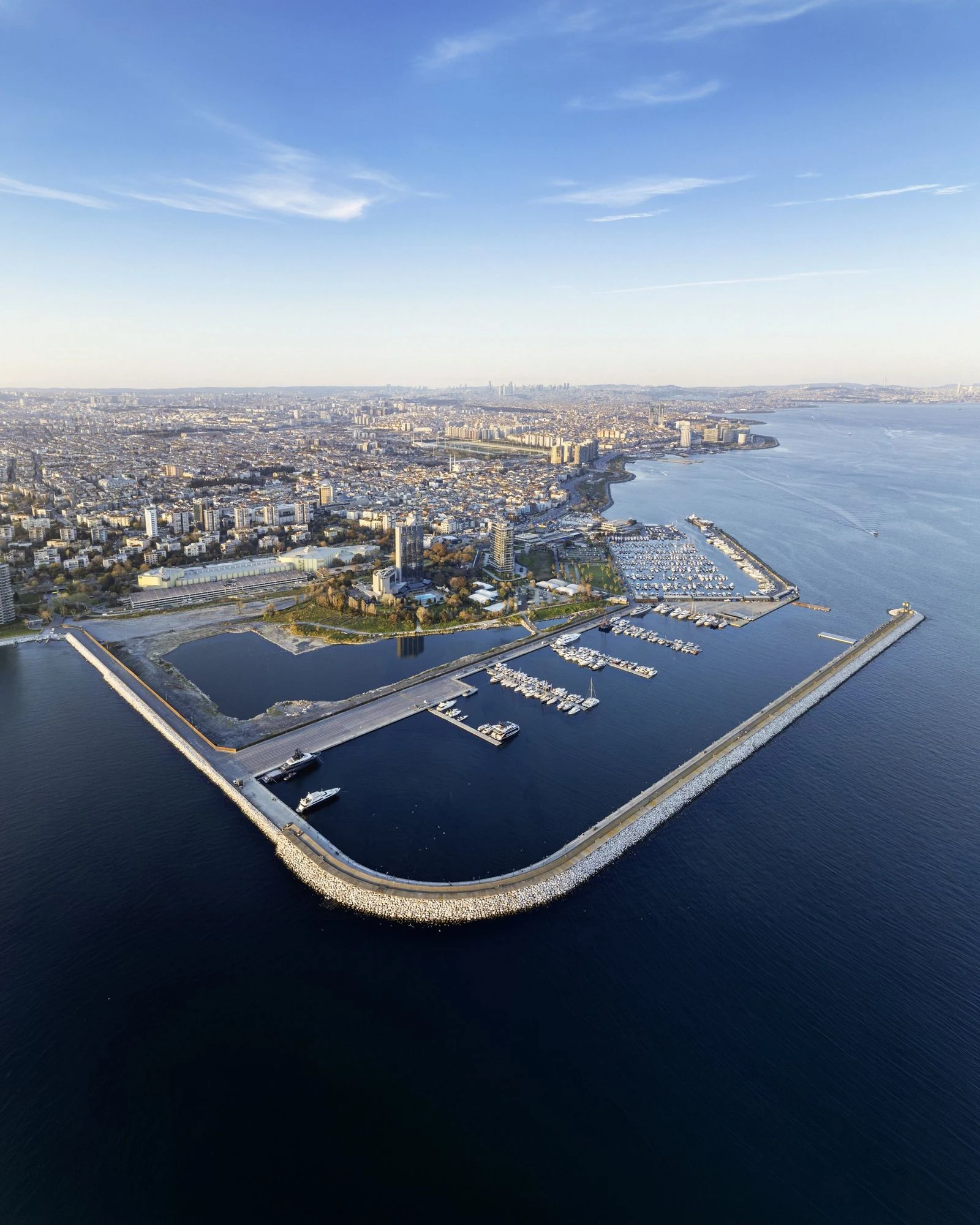 Ataköy Marina yarımadası ve dalgakıranın kuşbakışı görünümü; sıralı yat iskeleleri ve arkada İstanbul silüeti