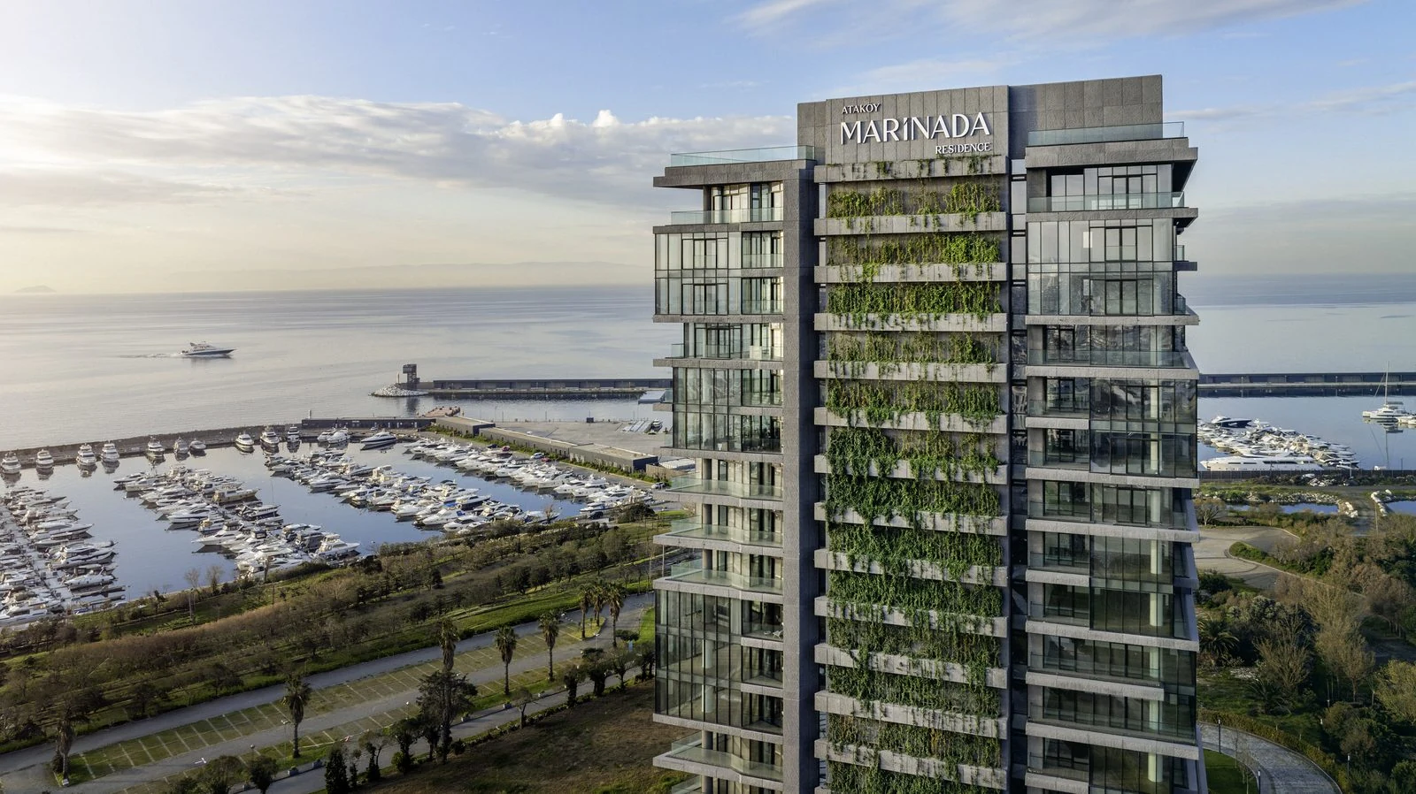 Gün batımında marinaya bakan Marinada Residence’ın yeşil teraslı cephesi ve marina promenadı